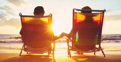 Couple Sitting on Lounge chairs on deck at sunset