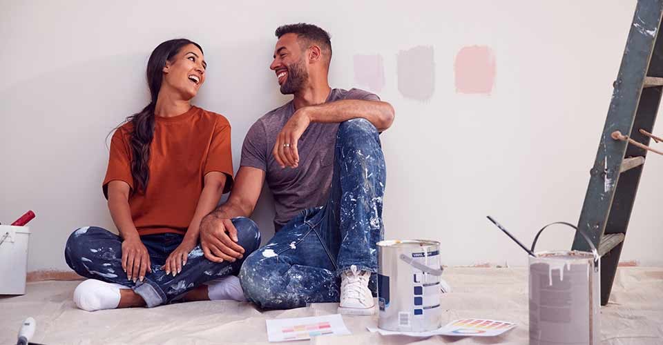 Couple Taking a Break From Painting on Wall as they Decorate Room in New Home Together
