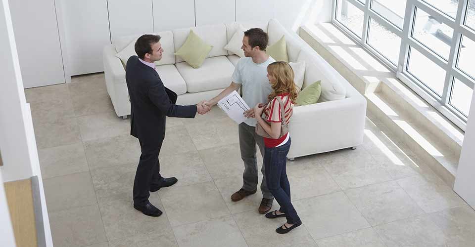 Elevated view of a real estate agent shaking hands with a man by woman in new home