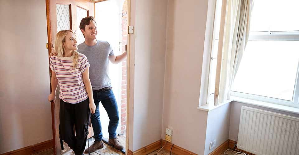 Excited Young Couple Opening Front Door of New Home
