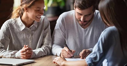 Excited young couple sign contract taking mortgage