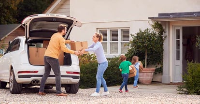 Family Outside New Home on Moving Day Loading or Unloading Boxes From Car