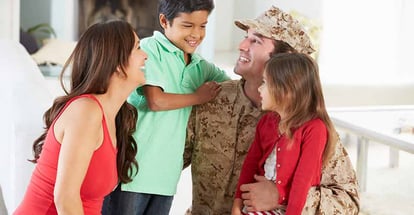 Family greeting military father inside their home