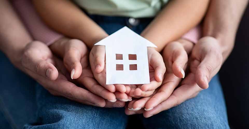 Family holding cutout paper house figure in hands