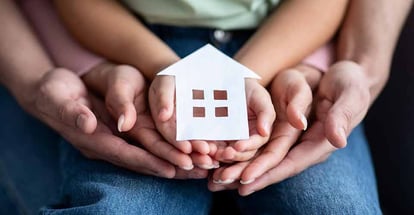 Family holding cutout paper house figure in hands
