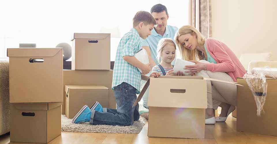 Family unpacking cardboard boxes at new home