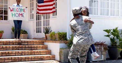 Family welcoming an african american soldier wearing uniform outside their house
