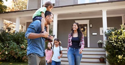 Father Gives Son Ride On Shoulders with Family Outside House