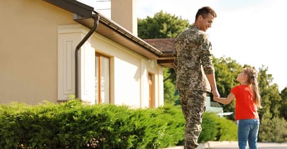 Father in military uniform with his little daughter outside their new house