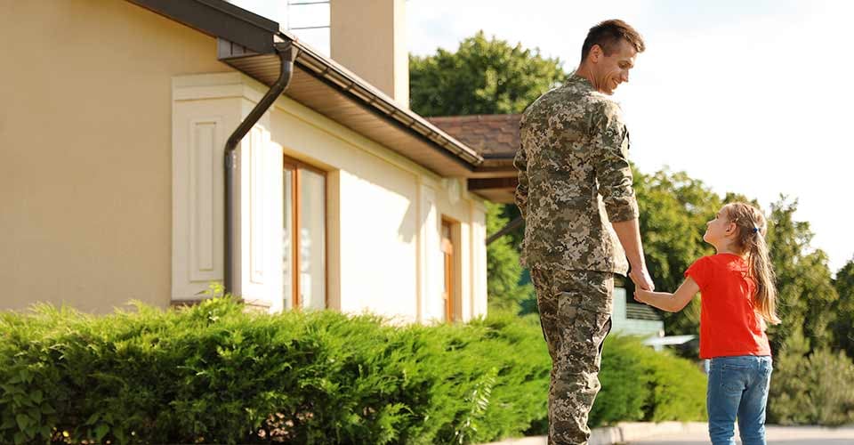 Father in military uniform with his little daughter outside their new house