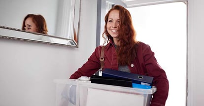 Female College Student Carrying Box Moving Into Accommodation