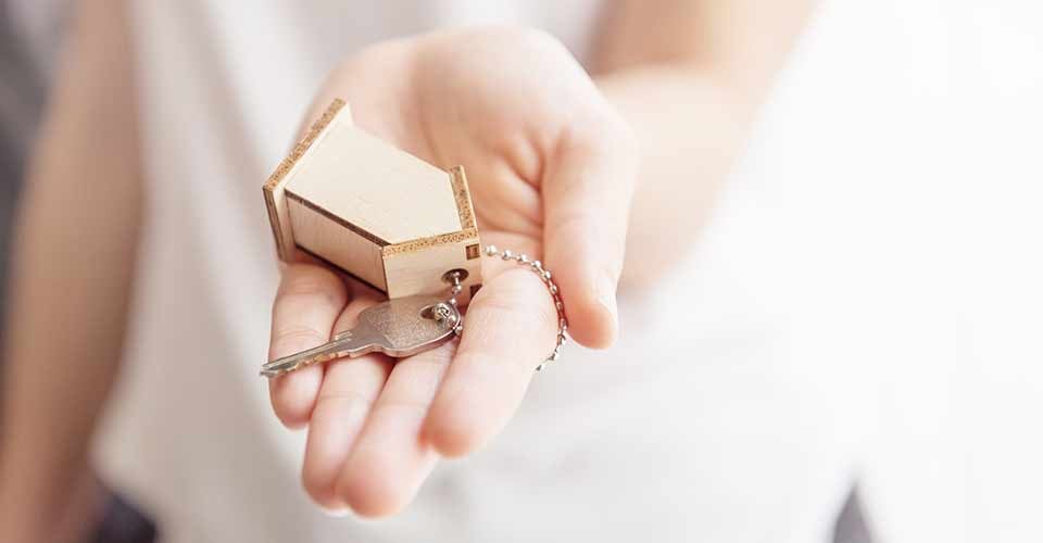 Female hand holding key and house shaped keychain