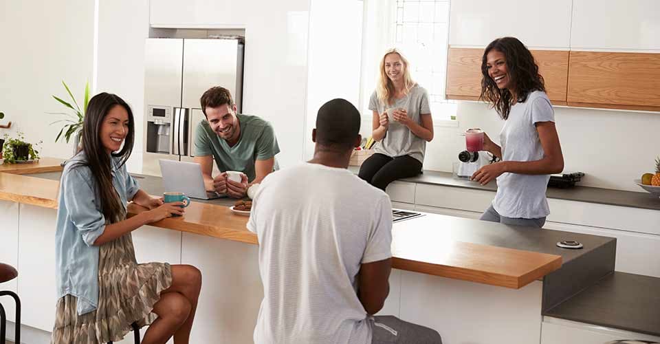 Friends Talking And Drinking Coffee In Modern Kitchen