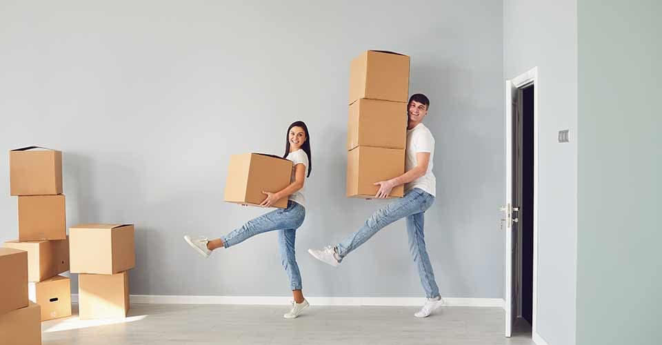 Funny couple with cardboard boxes smiling in a new home