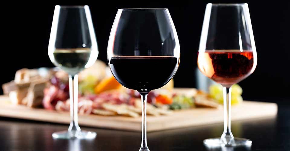 Glasses of red white and rose wine over a delicatessen table