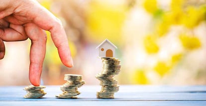 Gold coin stack with home model on top and loan for real estate investment