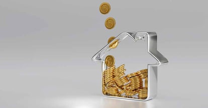 Golden coin falling into house shape piggy bank