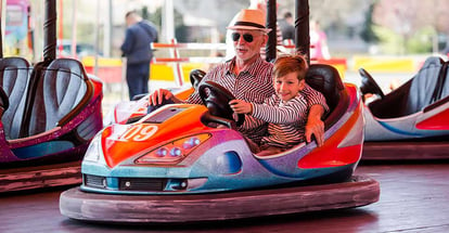 Grandfather and grandson having fun in bumper car