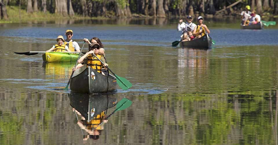 Group of adults and children canoeing on the river at Shingle Creek Regional Park in Kissimmee Florida