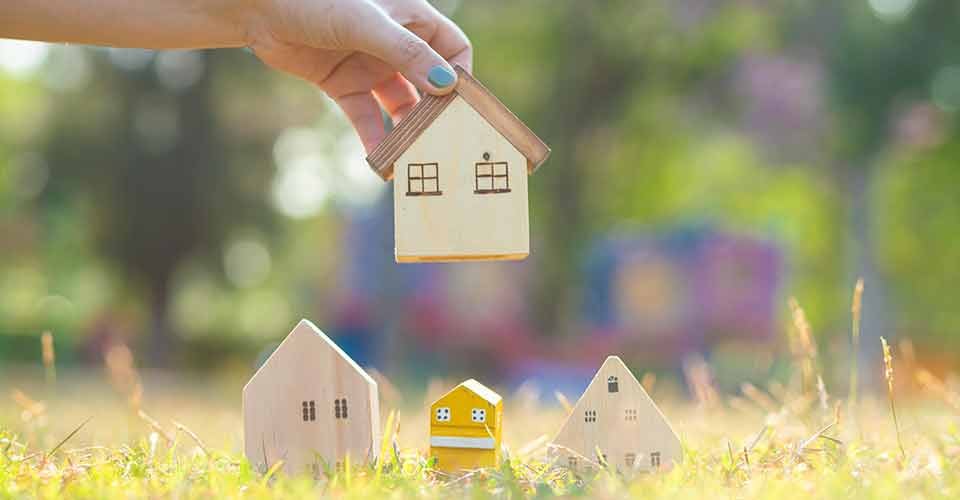 Hand choose a wooden house on green grass