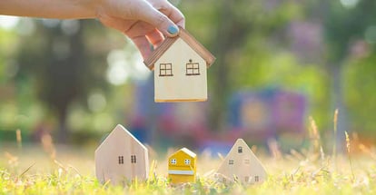 Hand choose a wooden house on green grass