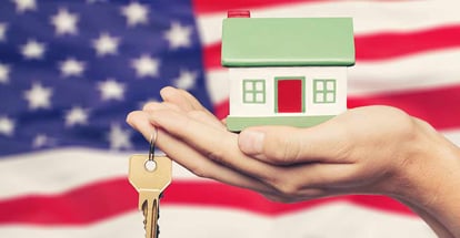 Hand holding a model of house and key on the US flag background