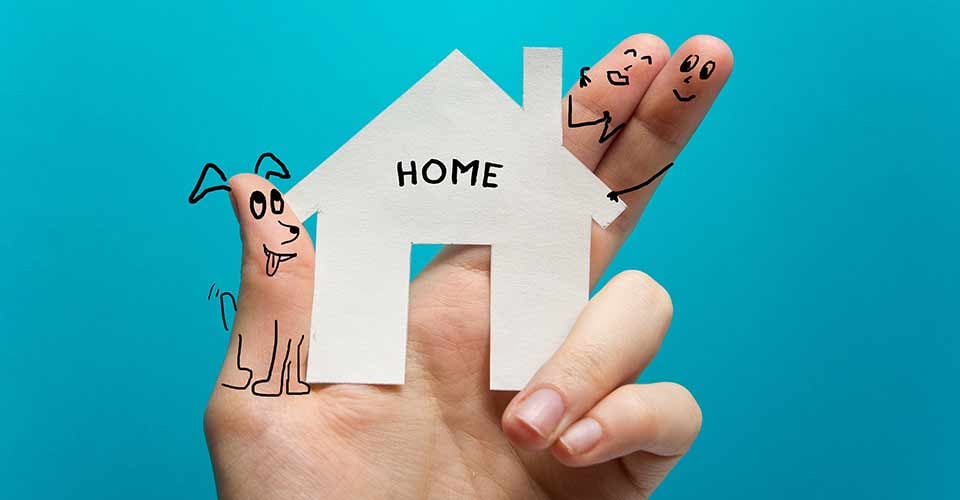 Hand holding white paper house figure on blue background