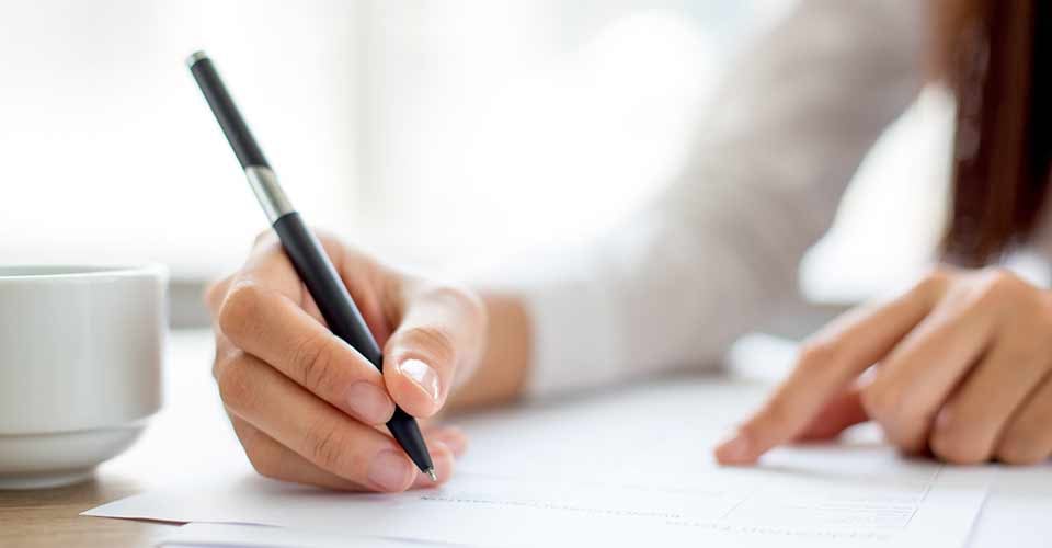 Hand of businesswoman writing on paper in office