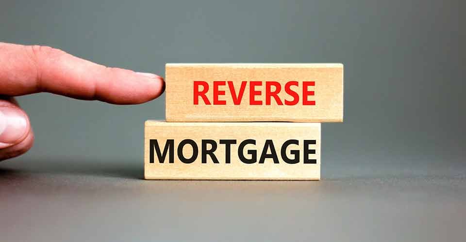 Hand pointing at reverse mortgage words on wooden blocks