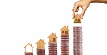Hand put house model on row of coins stack for real estate investment