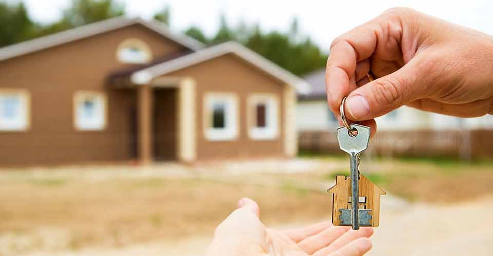 Hand with a key and a wooden key ring after home purchase