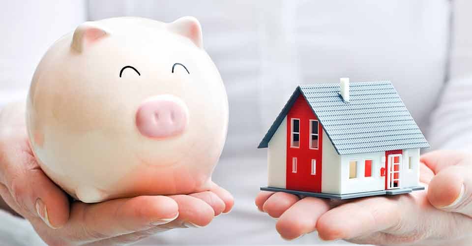 Hands holding a piggy bank and a house model