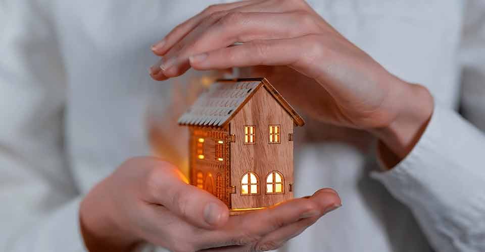 Hands holding a wooden house model