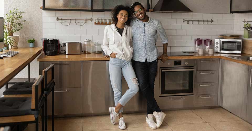 Happy African American couple standing in modern kitchen at home