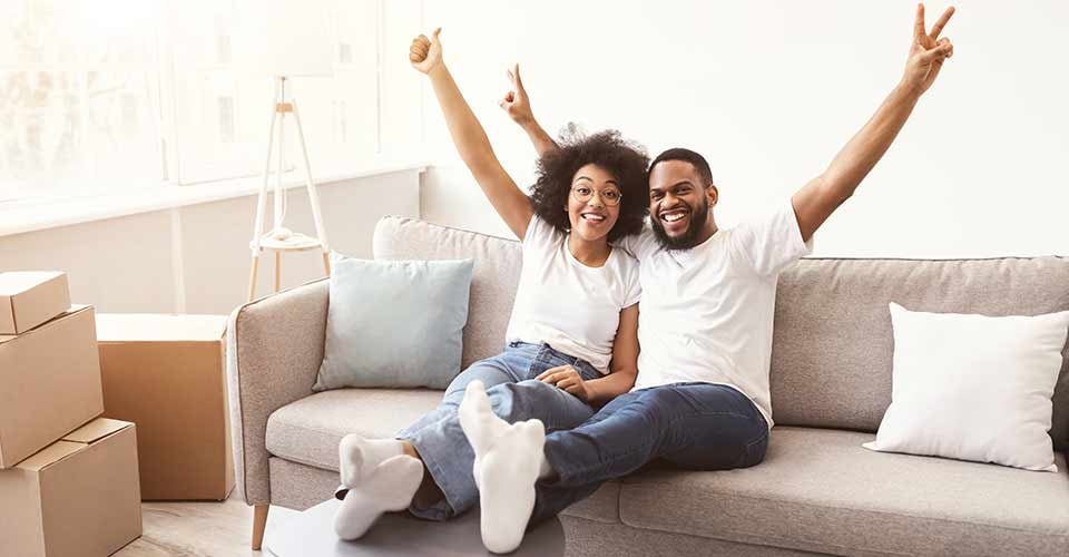 Happy Couple Celebrating Real Estate Purchase Sitting Among Unpacked Boxes