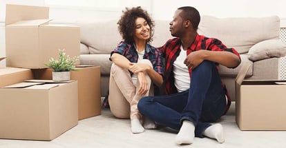Happy african american couple unpacking moving boxes in new house