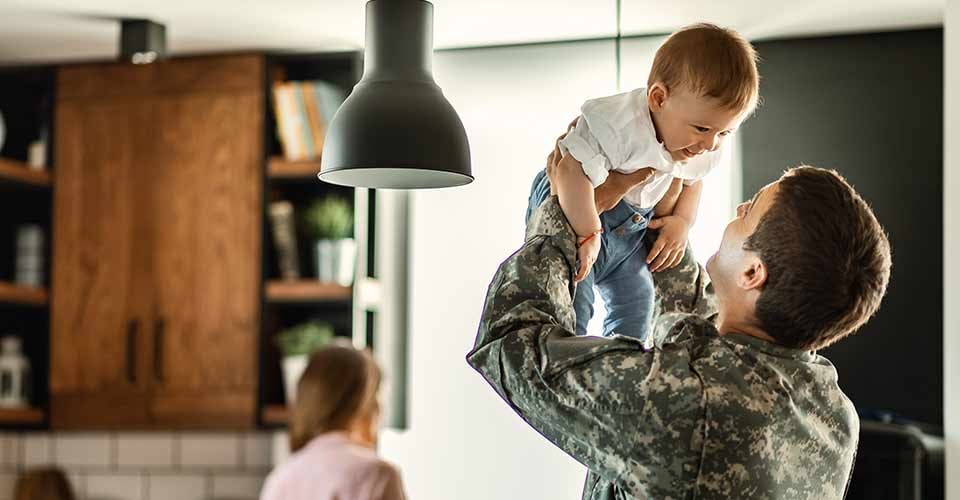 Happy baby having fun with his military dad at new home