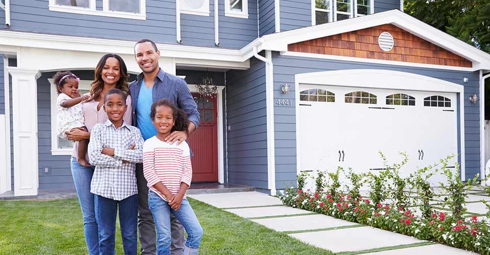 Happy black family standing outside their house