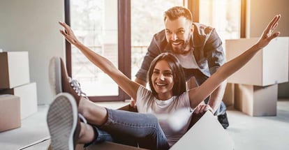 Happy couple having fun with cardboard boxes in new house