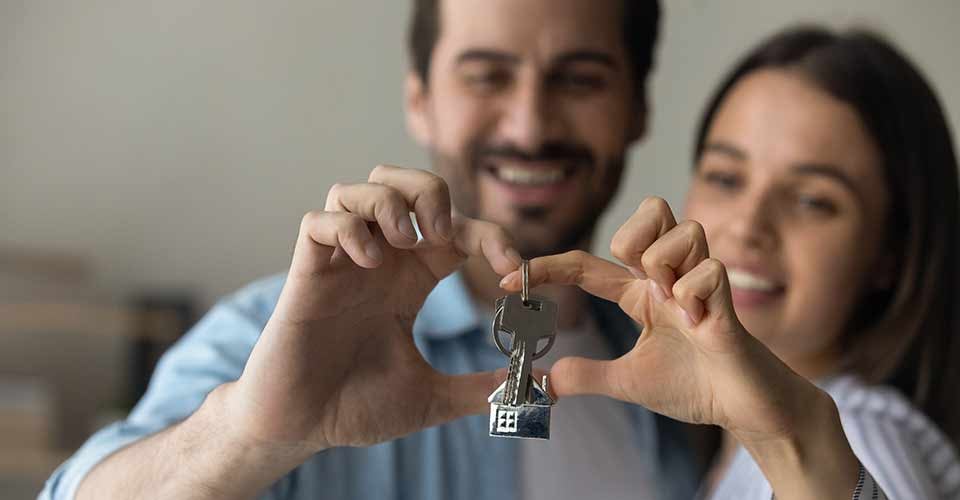 Happy couple holding keys at new home