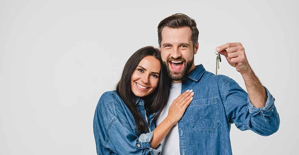 Happy couple holding new house keys and celebrating home purchase