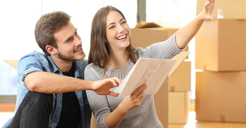 Happy couple planning decoration when moving home sitting on the floor