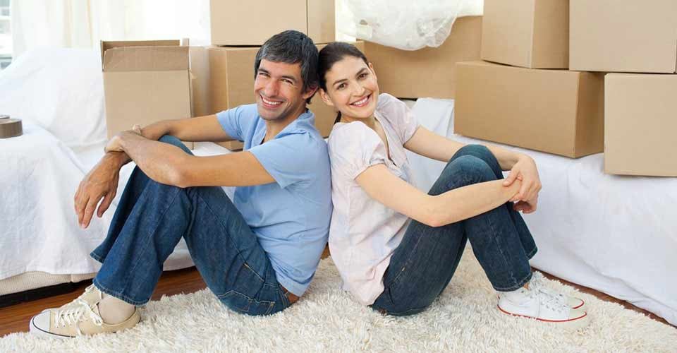 Happy couple relaxing sitting on the floor while moving house