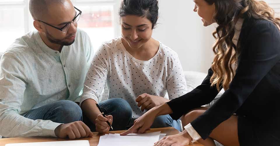 Happy couple signing contract at meeting after successful negotiation with realtor