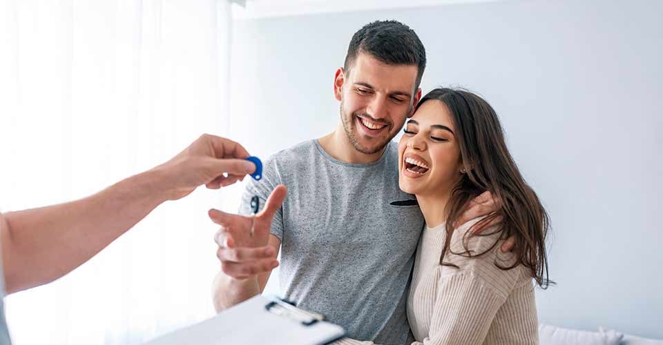 Happy couple taking their new house keys from real estate agent and smiling