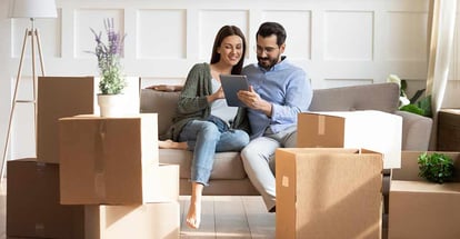 Happy family sitting on couch among cardboard boxes in new house