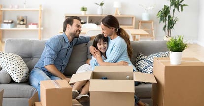 Happy family sitting on couch in living room at new home
