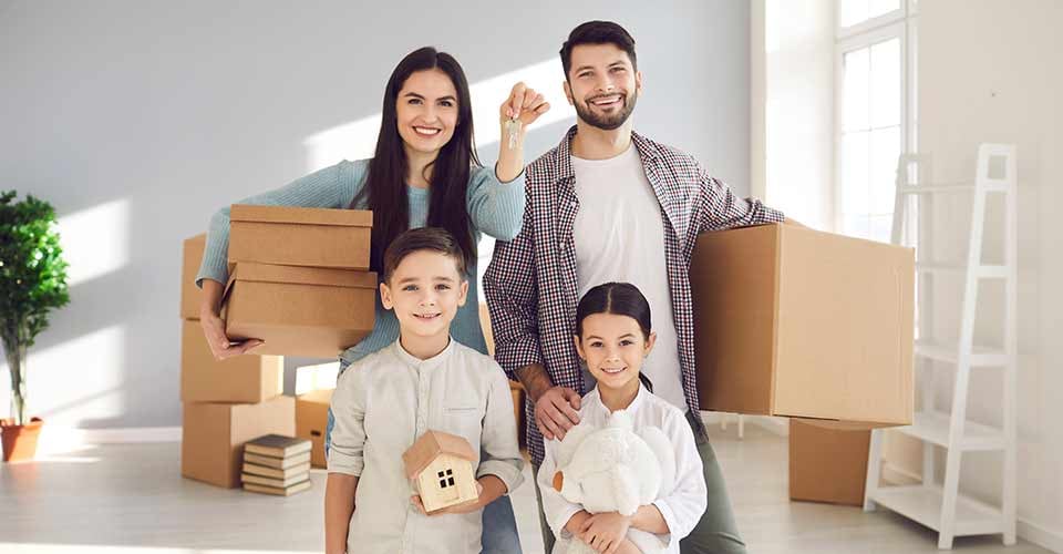 Happy family smiling and showing keys to their new home on moving day