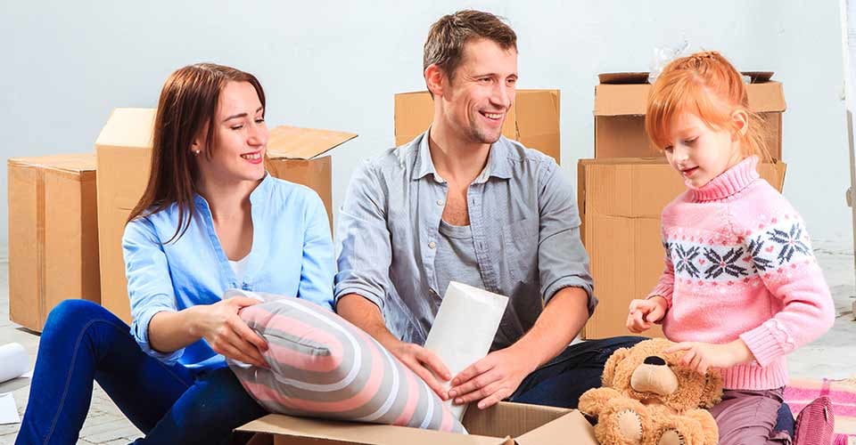 Happy family unpacking boxes after moving to new home