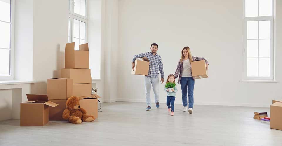 Happy family with children moving with boxes in a new house
